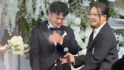 Bride gives gift on wedding stage as groom gets emotional with joy